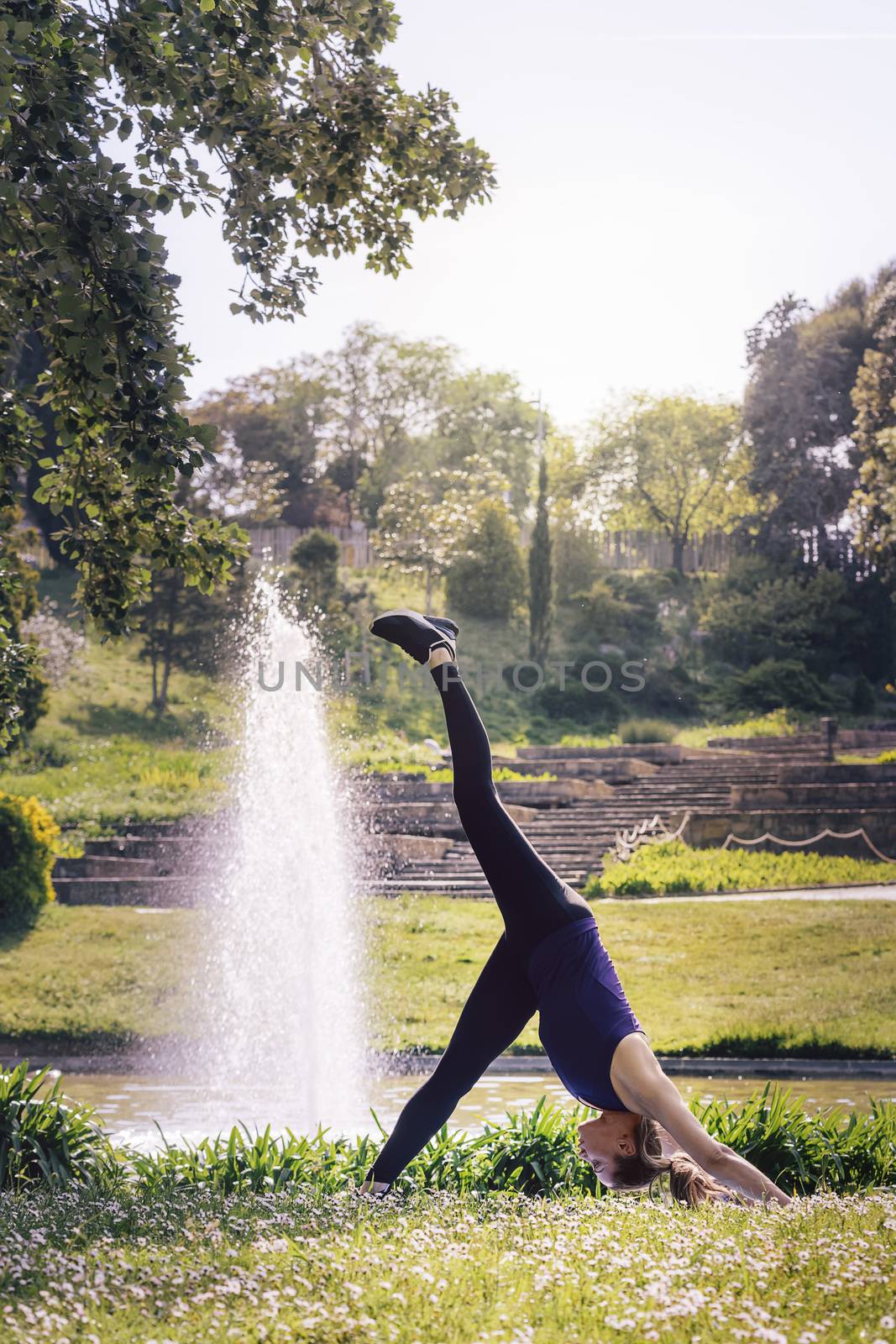 vertical photo of a young sports woman doing meditation yoga exercises and relaxing outdoors in the park, modern healthy lifestyle and sport concept
