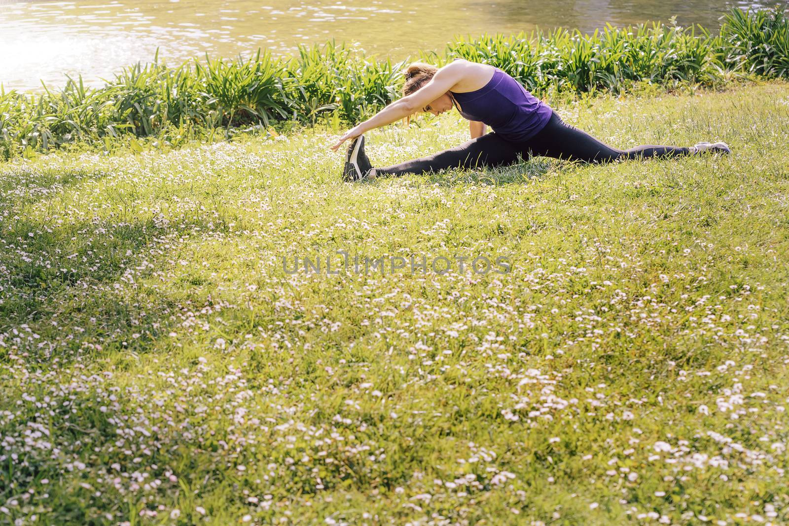woman doing flexibility exercises on the grass by raulmelldo