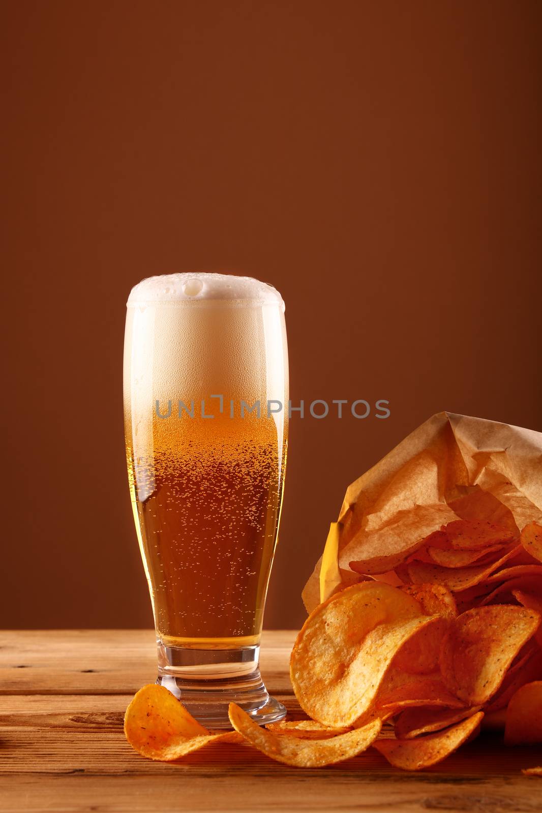 Close up beer glass and potato chips over brown by BreakingTheWalls