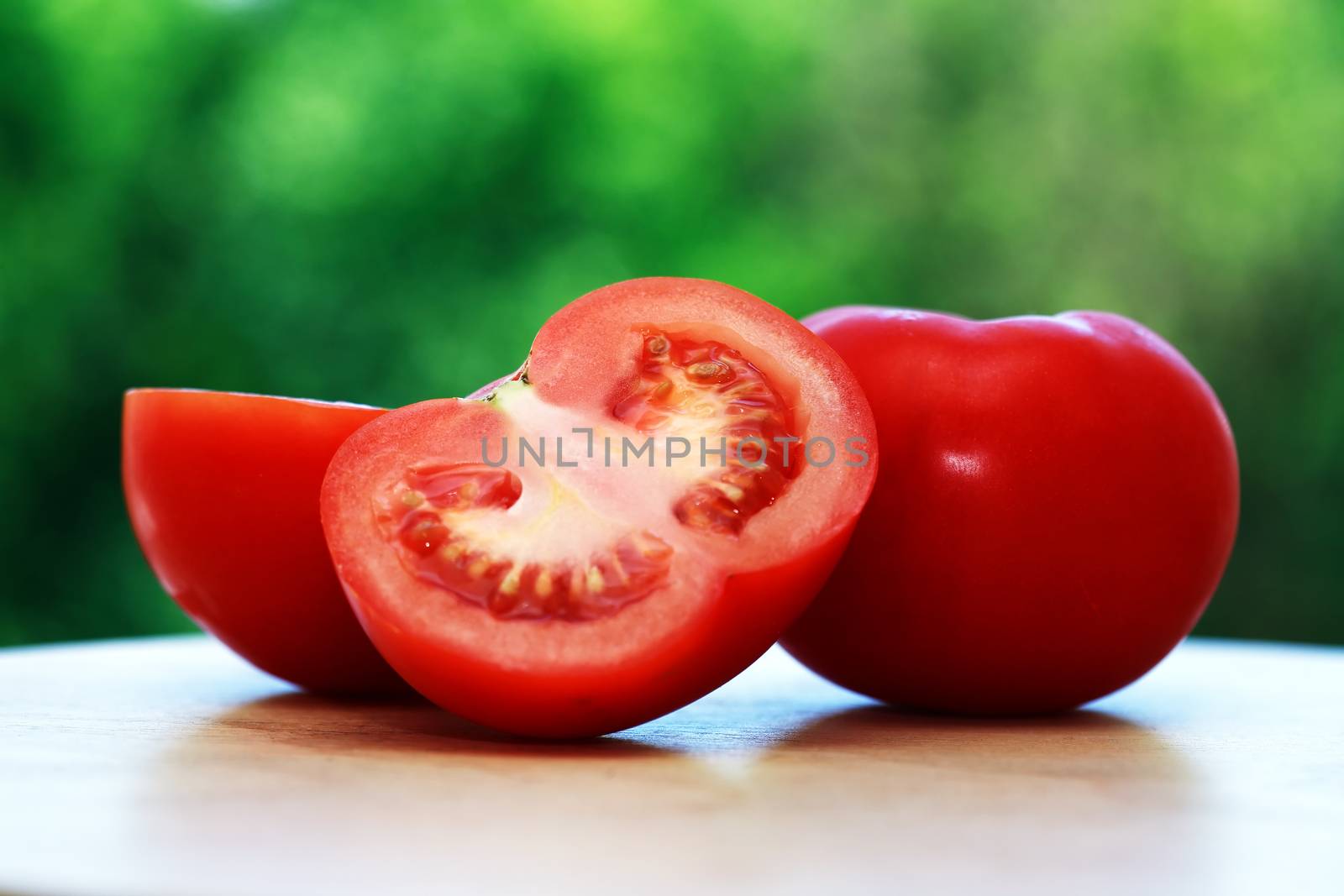 Few red ripe tomatoes against morning nature background