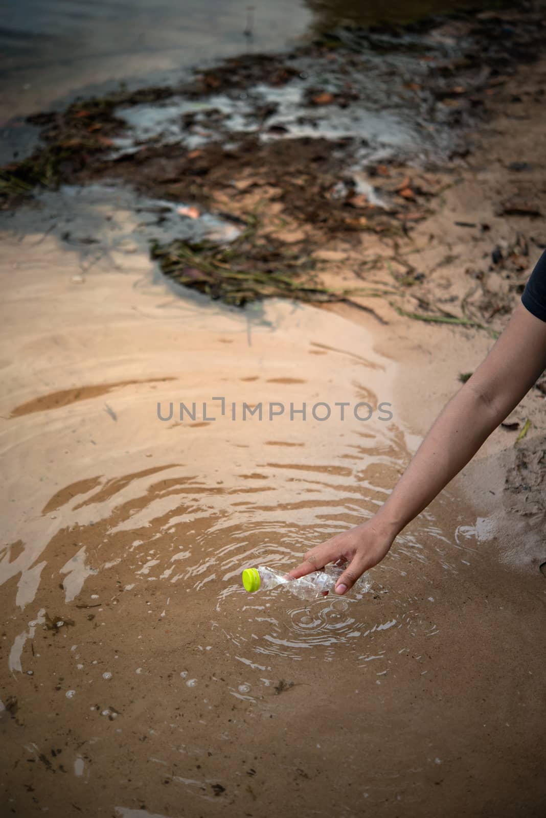 hand pick up plastic bottle from water. save environment and beat plastic pollution , Selective focus