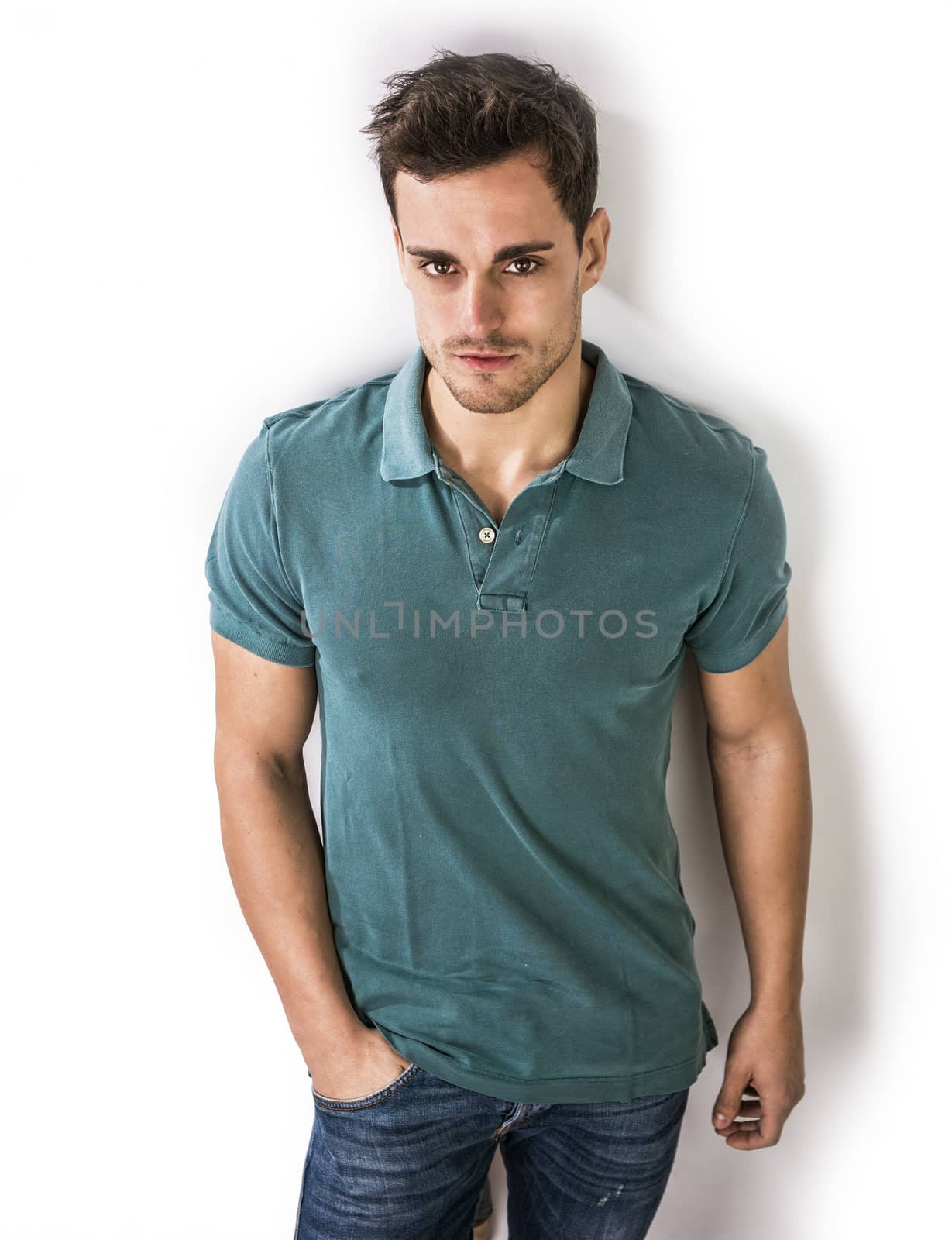 Handsome young man in green shirt and jeans posing isolated on white background in studio,