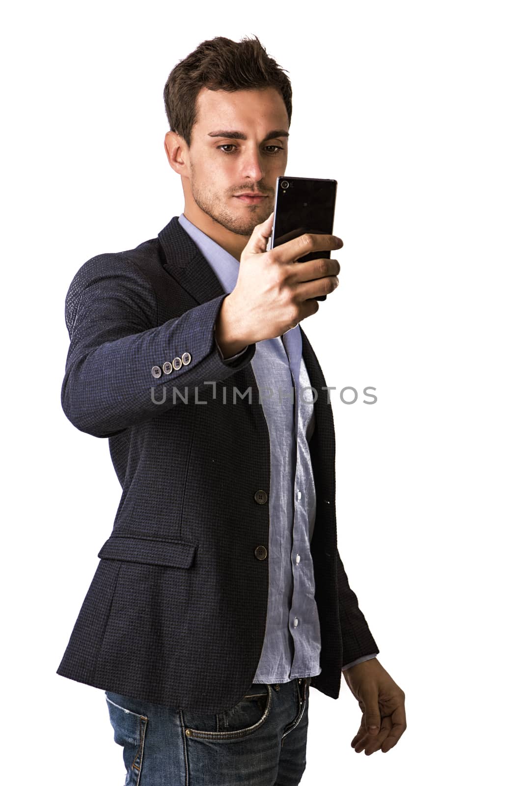 Handsome man taking selfie photo on cell phone or mobile, on black background in studio shot. Looking at cellphone