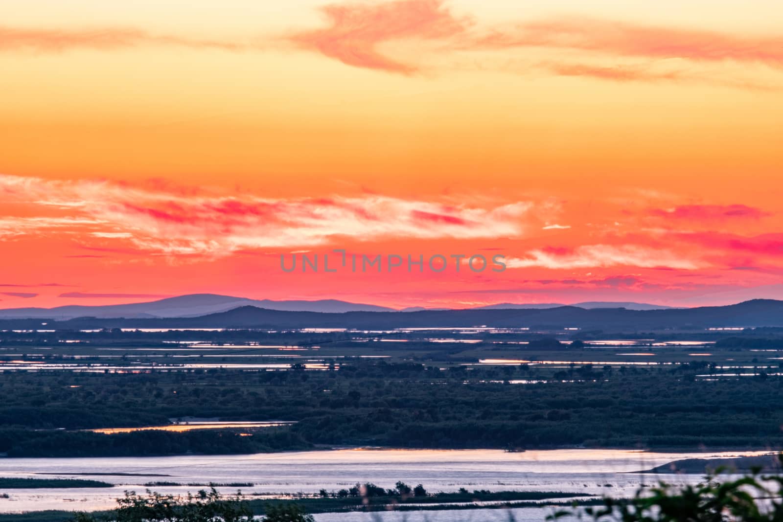 Sunset on the embankment of the Amur river in Khabarovsk. The sun set over the horizon. The embankment is lit by lanterns.