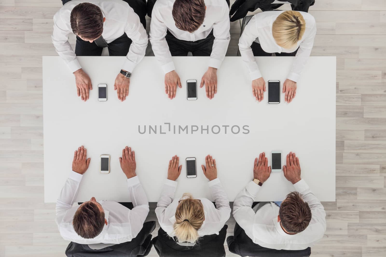 Top view of business people sitting around the table and using smartphones with blank screen