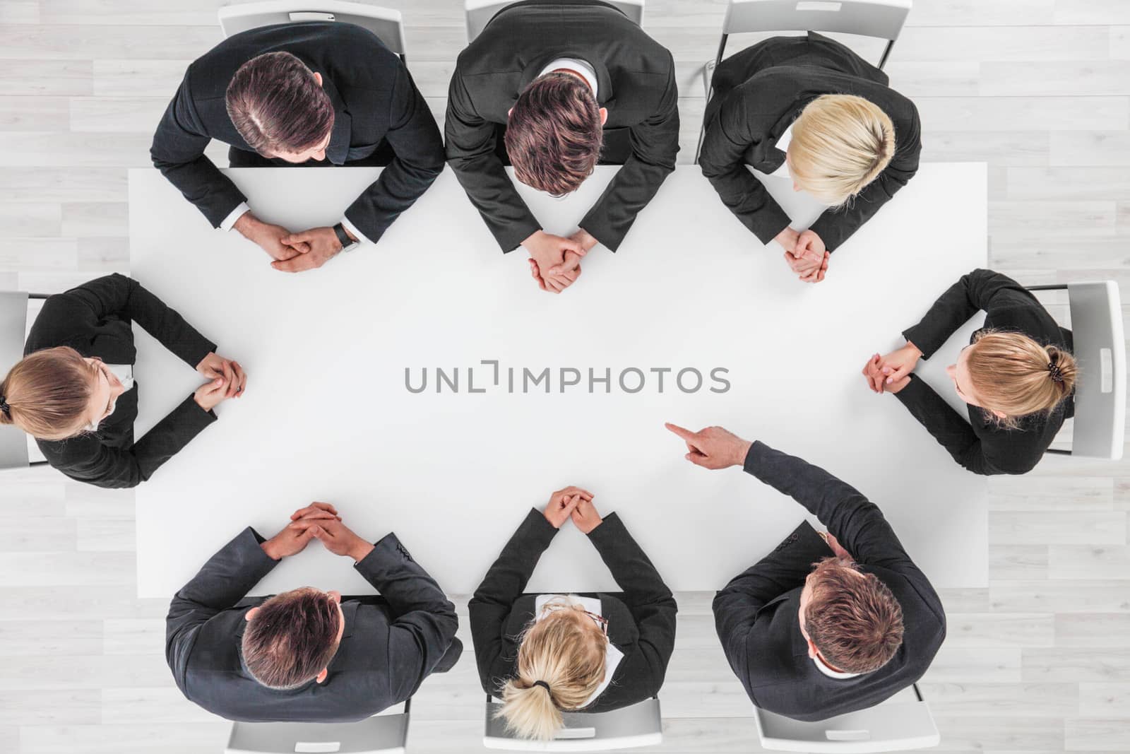 Business, people and team work concept - close up of creative team sitting at table and pointing finger to blank copy space for text