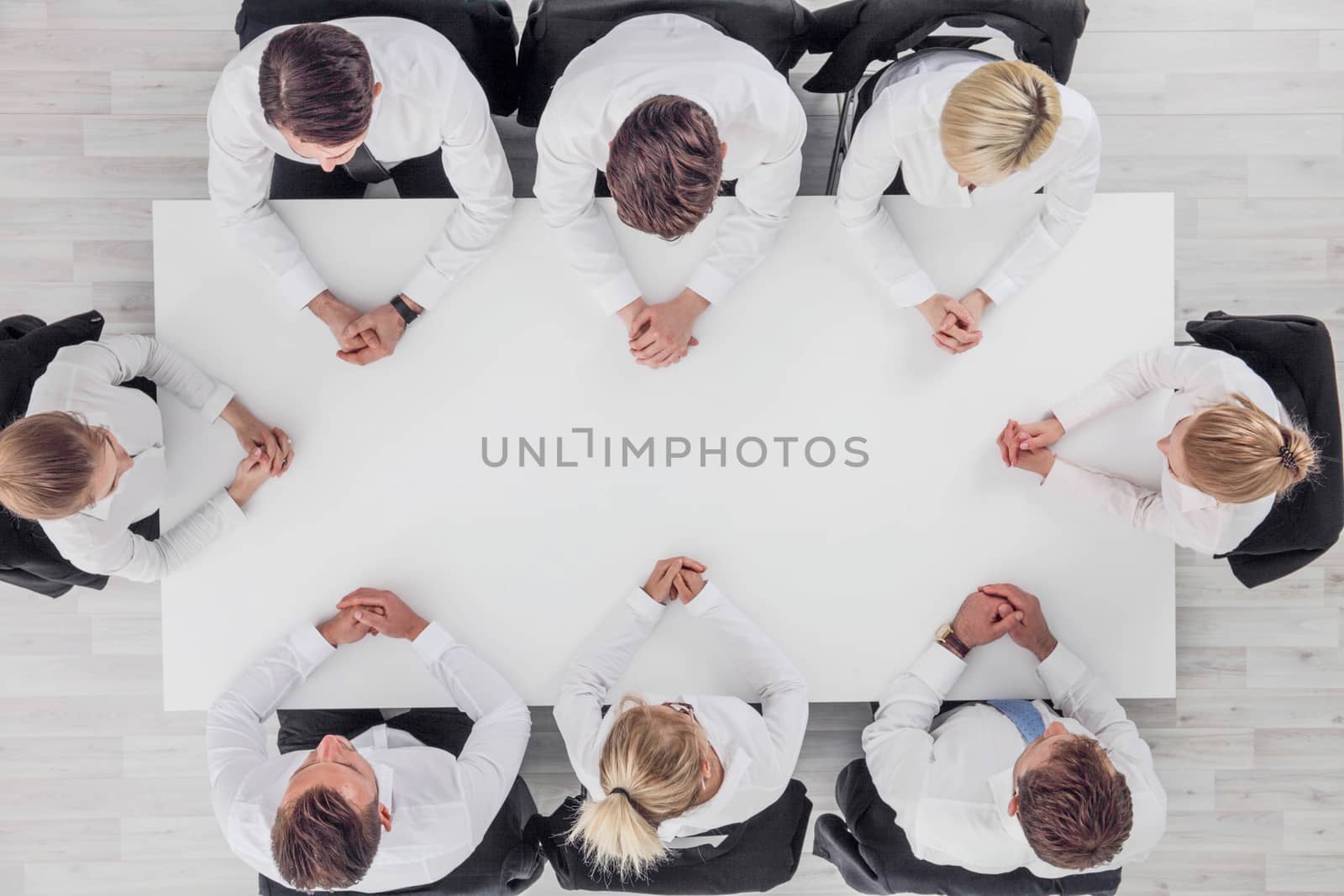 Business team sitting around white table, white copy space for text
