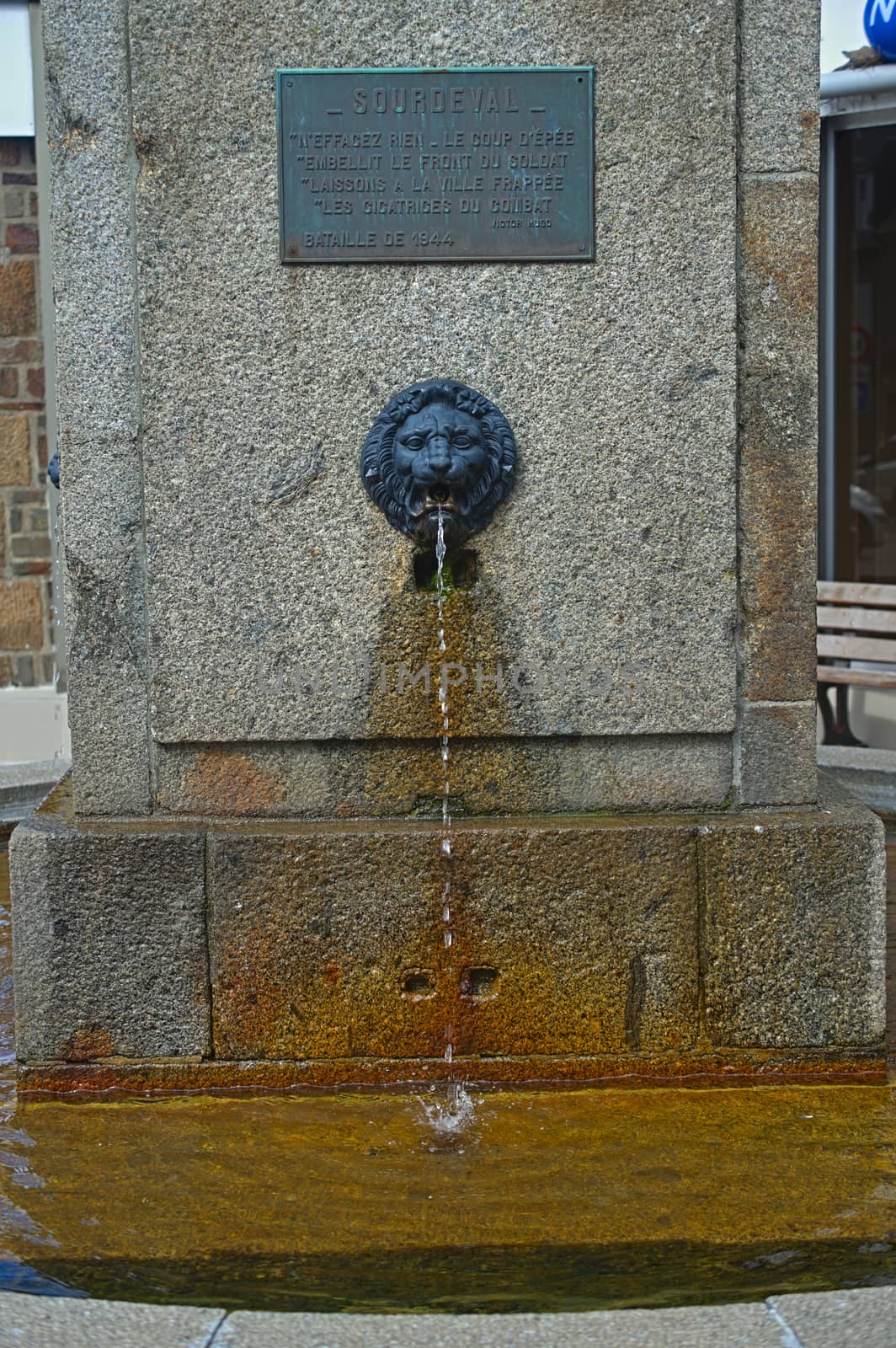 Water dripping from lions head at fountain in Surdeval Normandy France