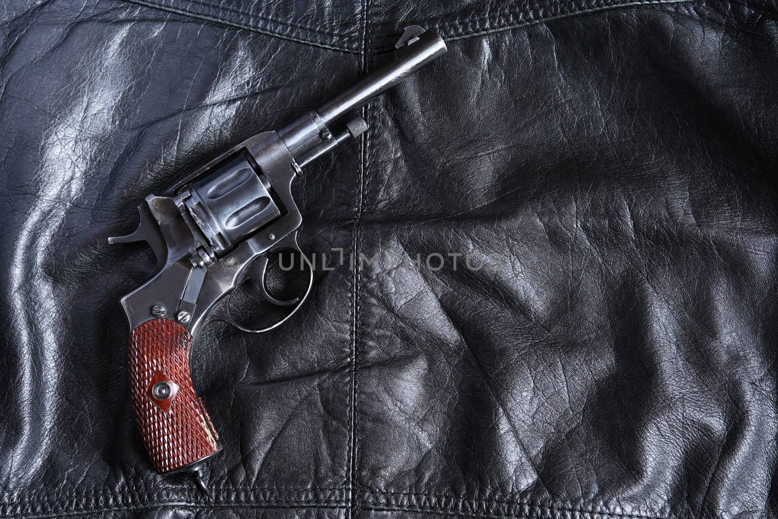 Old revolver on black leather background with free space