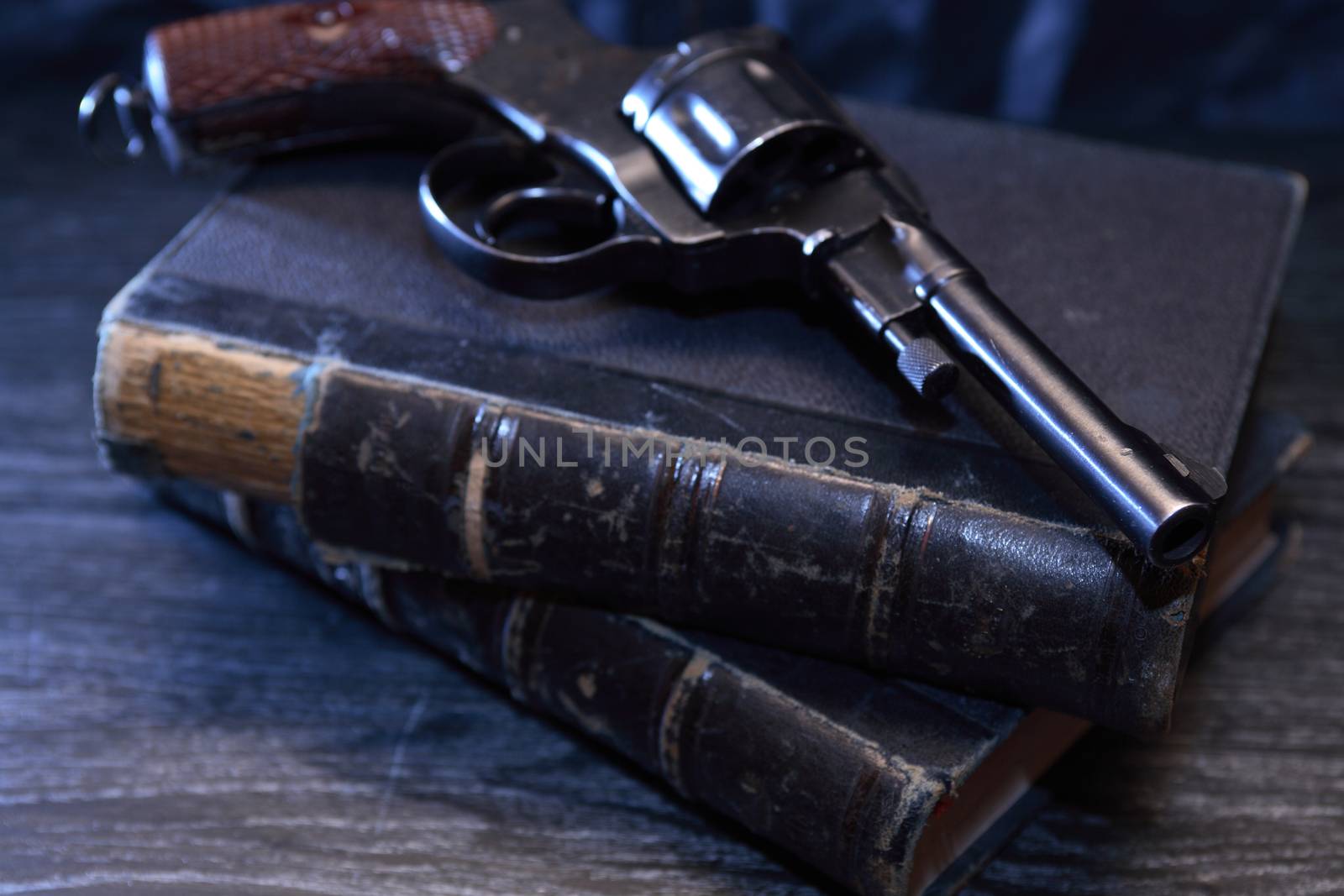 Vintage still life. Old handgun on book against dark background