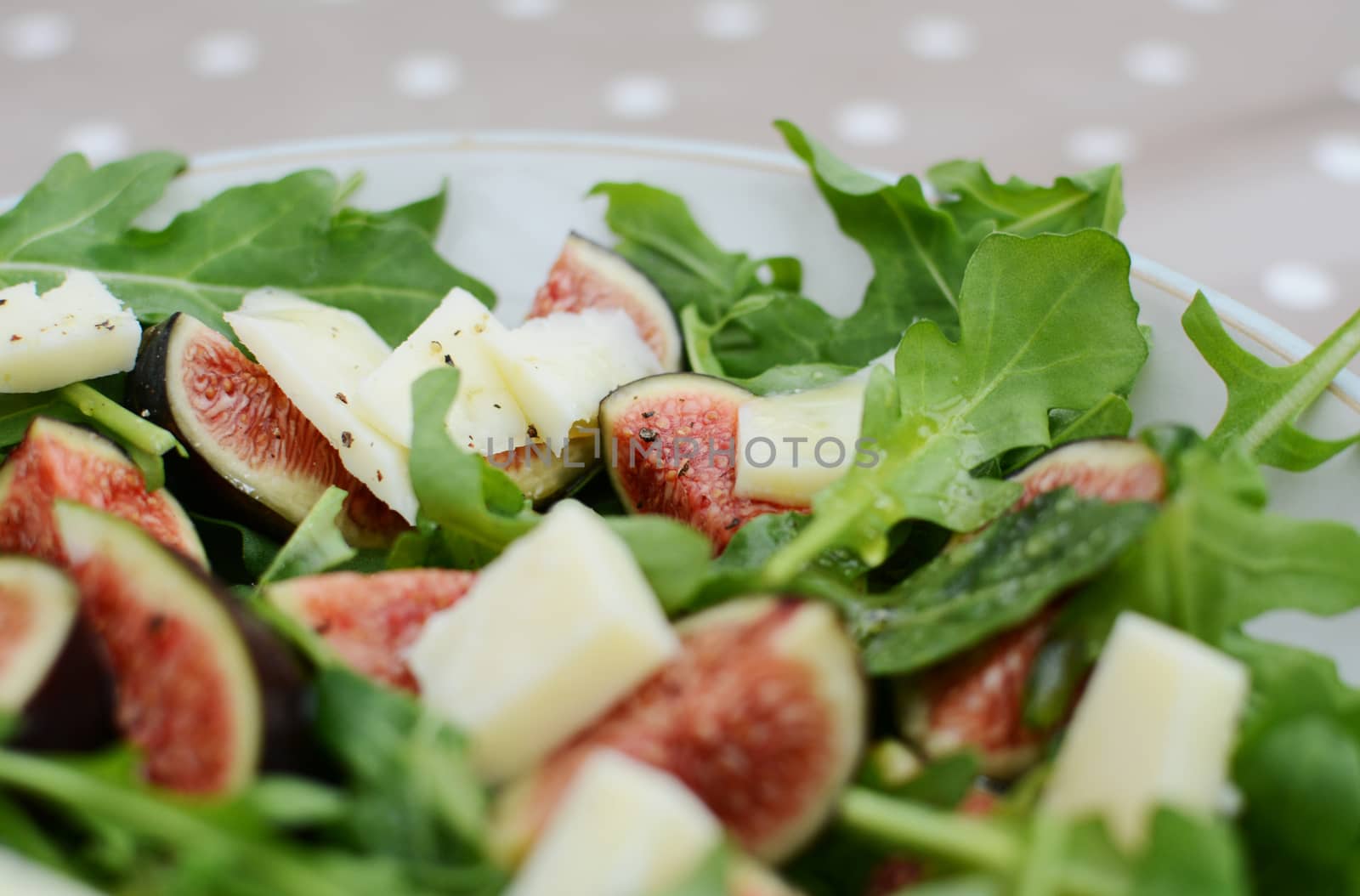 Fresh fig salad with pieces of salty pecorino and green rocket leaves in selective focus