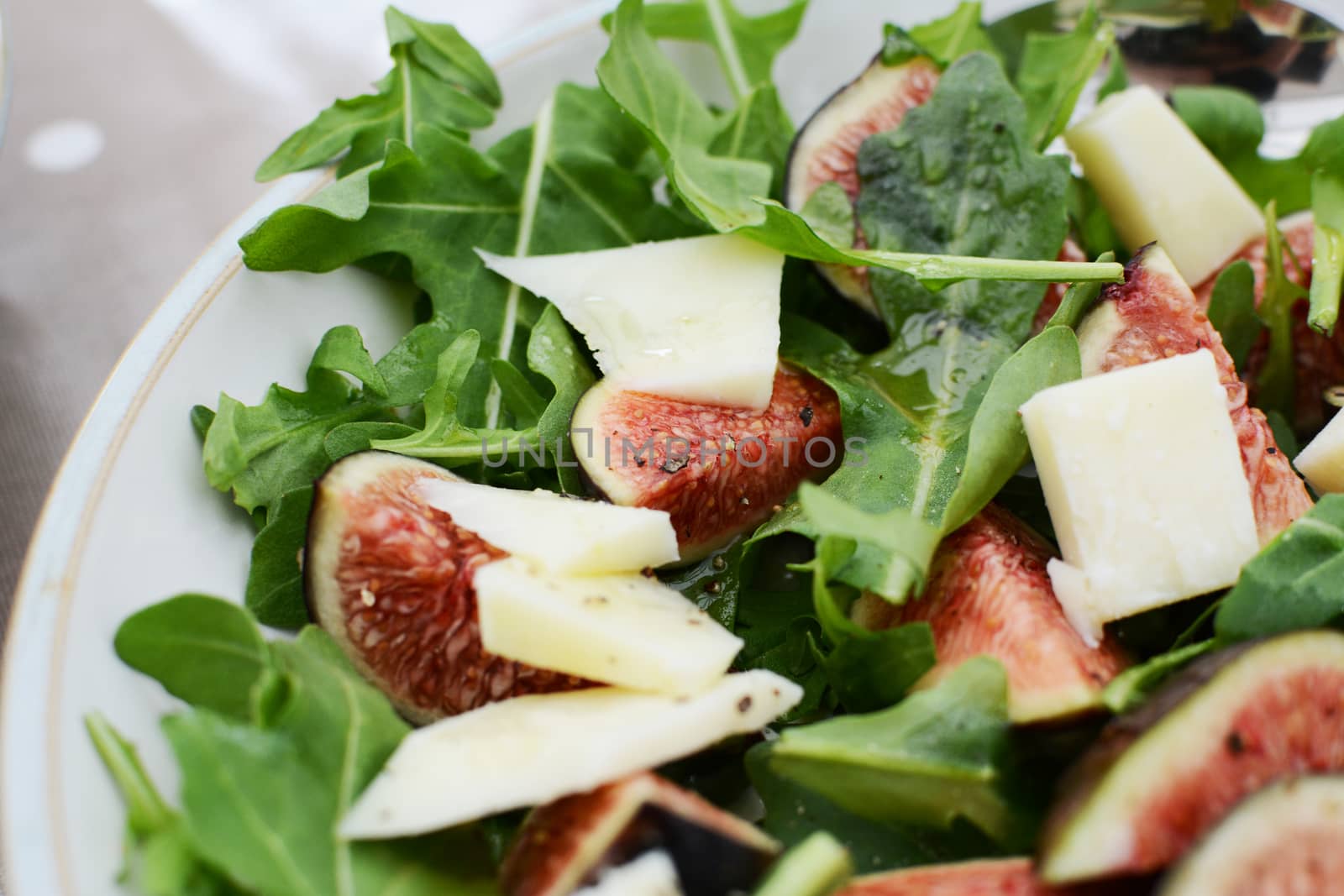 Fresh fig and pecorino chunks on a bed of green rocket leaves, drizzled with honey for a tasty salad