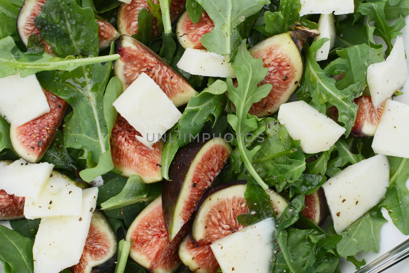 Wedges of fresh figs, chunks of pecorino cheese and green rocket leaves in a fresh summer salad