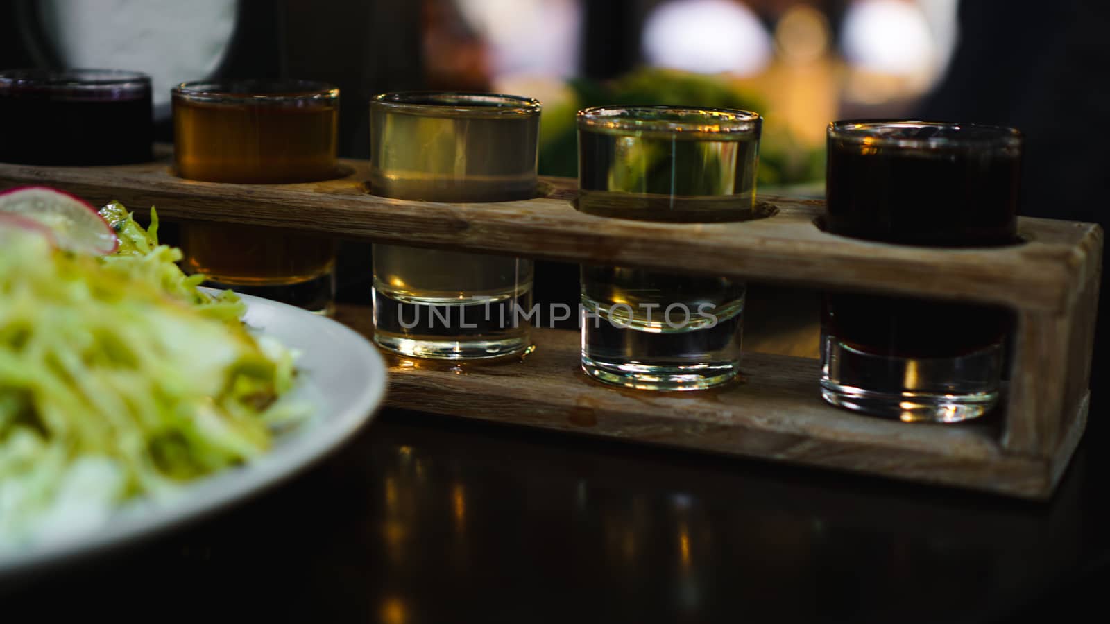 Set of shots in one row, six servings on a wooden stand and grren salad. Drink for the menu restaurant, bar, cafe