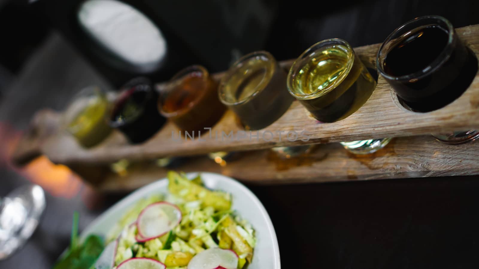 Set of shots in one row, six servings on a wooden stand and grren salad by natali_brill