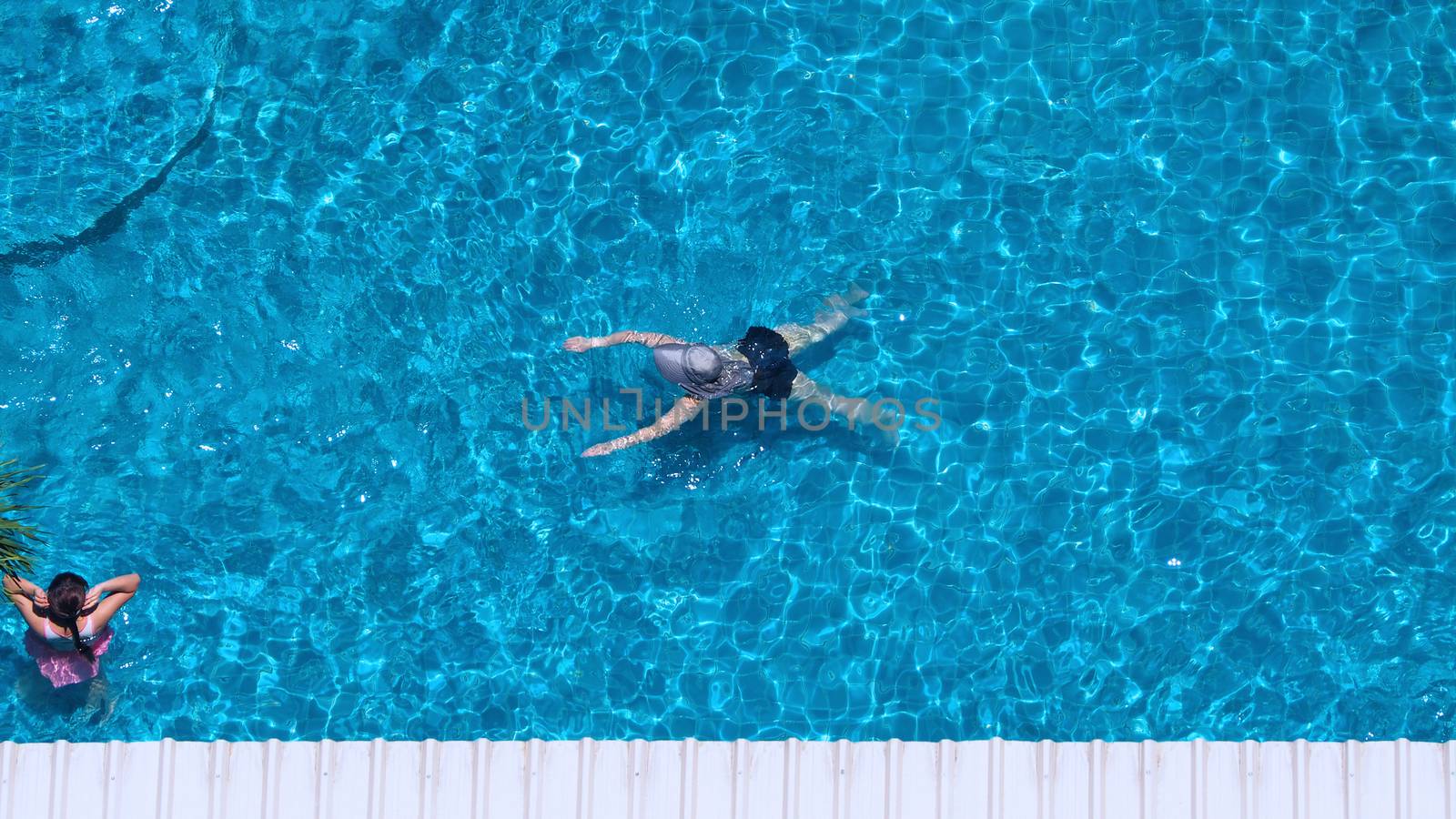 Swimming pool top view angle which blue color clear water and sun light reflect on surface texture and concept images for relaxation or vacation or sport in the tropical summer and for healthy lifestyle