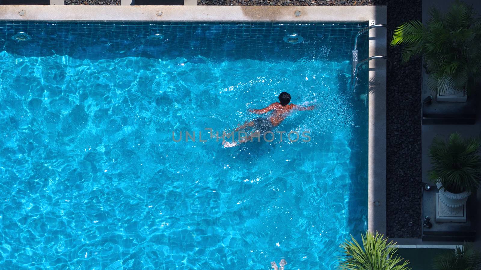 Swimming pool top view angle which blue color clear water and sun light reflect on surface texture and concept images for relaxation or vacation or sport in the tropical summer and for healthy lifestyle