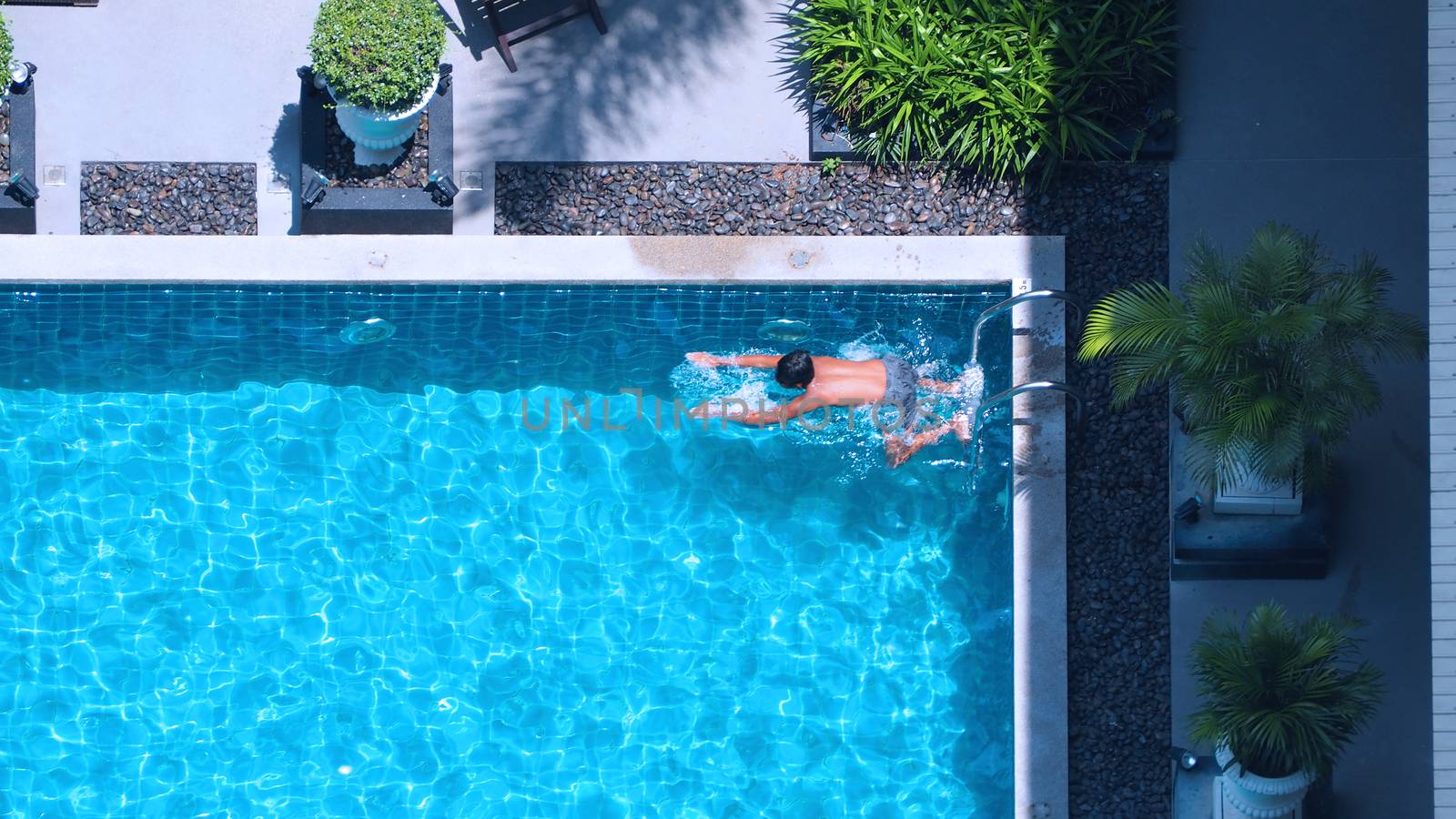 Swimming pool top view angle which blue color clear water and sun light reflect on surface texture and concept images for relaxation or vacation or sport in the tropical summer and for healthy lifestyle