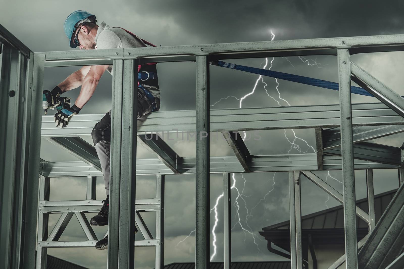 Construction Worker at Height During Thunderstorm with Lightnings in a Background. Contractor Safety.