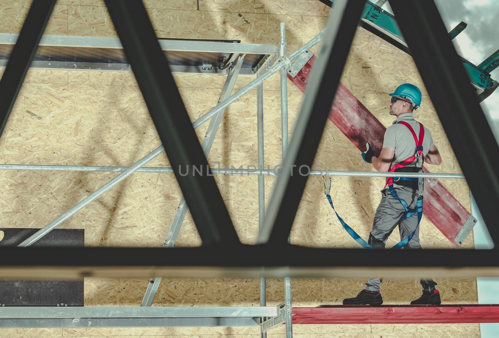 Construction Scaffolding Building by Caucasian Contractor Worker. Safety Harness Equipment. Construction Industry Theme.