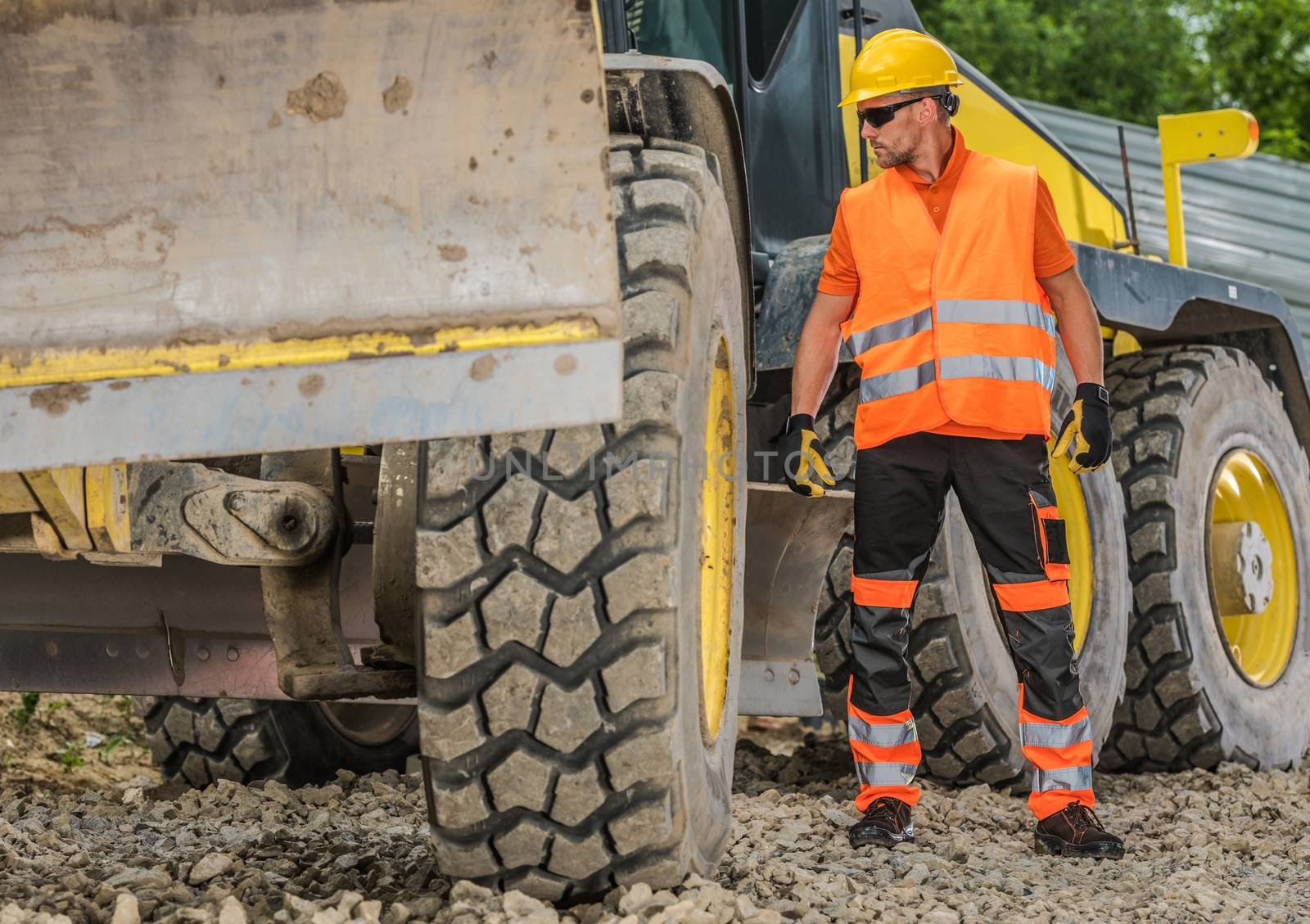 Heavy Construction Job. Caucasian Road Building Machinery Operator in His 30s Wearing Hard Hat.