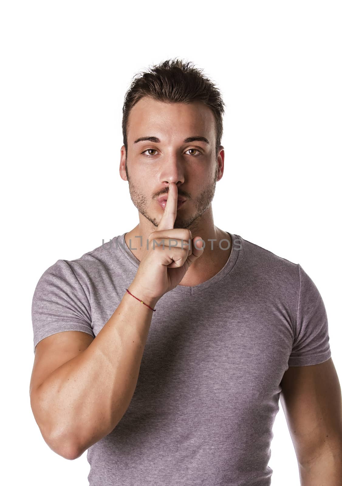 Attractive young man gesturing Hush or Silence with finger on mouth and nose, shushing isolated on white background