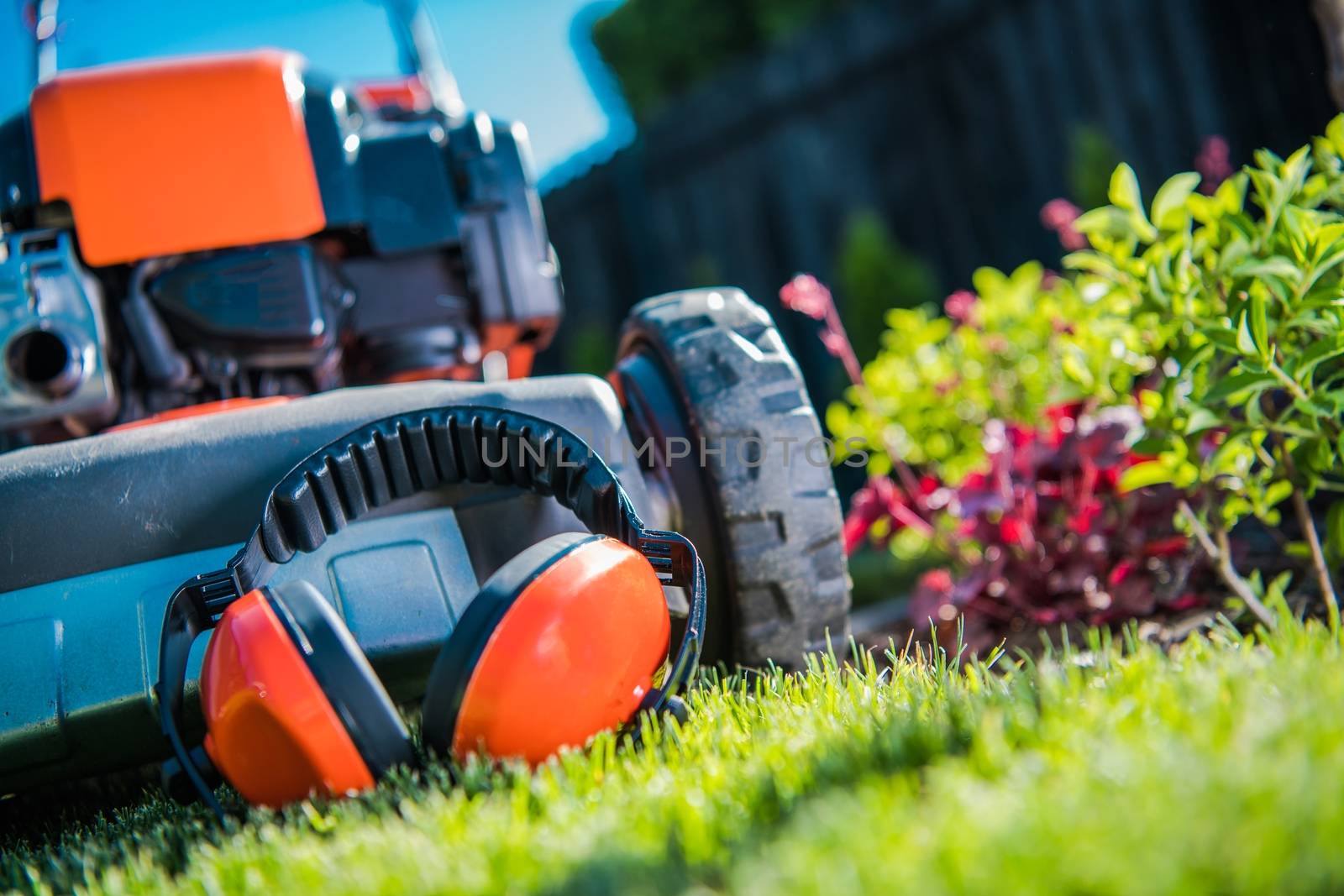 Hearing Protection While Working with Power Tools in the Garden. Ear Protectors and the Lawn Mower Closeup Photo.