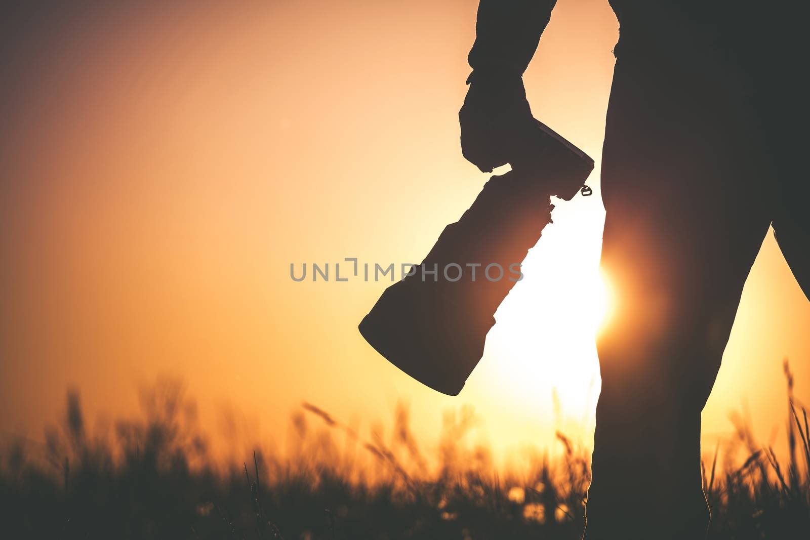 Safari Outdoor Photographer at Sunset. Silhouette of Men Keeping Digital Camera in Hand with Large Telephoto Lens For the Better Wildlife Closeups.
