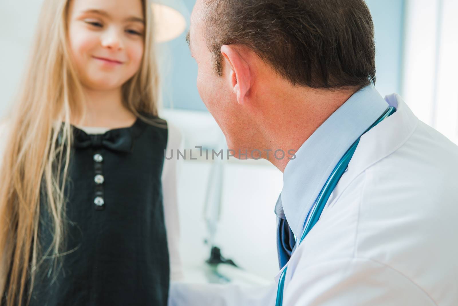 Pediatrician Senior Doctor in His 50s Talking To Caucasian Girl in the Hospital Room.