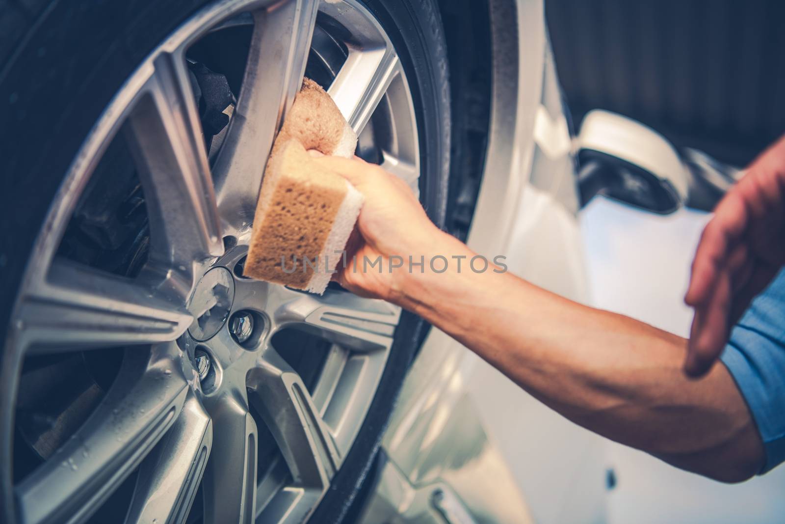 Men Cleaning Car Alloy Wheel. Vehicle Washing and Detailing Concept Photo.