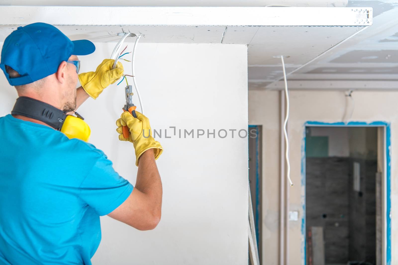 Electric Technician at Work Preparing Apartment Electric System Cables For Outlets Installation.