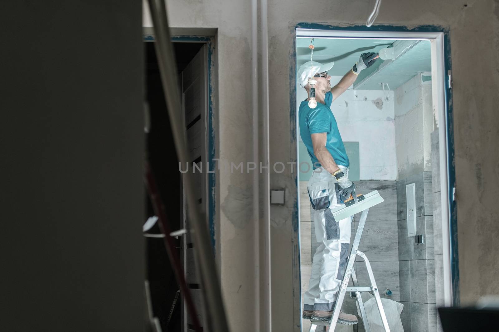 Apartment Remodeling Job. Caucasian Worker in His 30s Patching Drywall in the Remodeled Bathroom