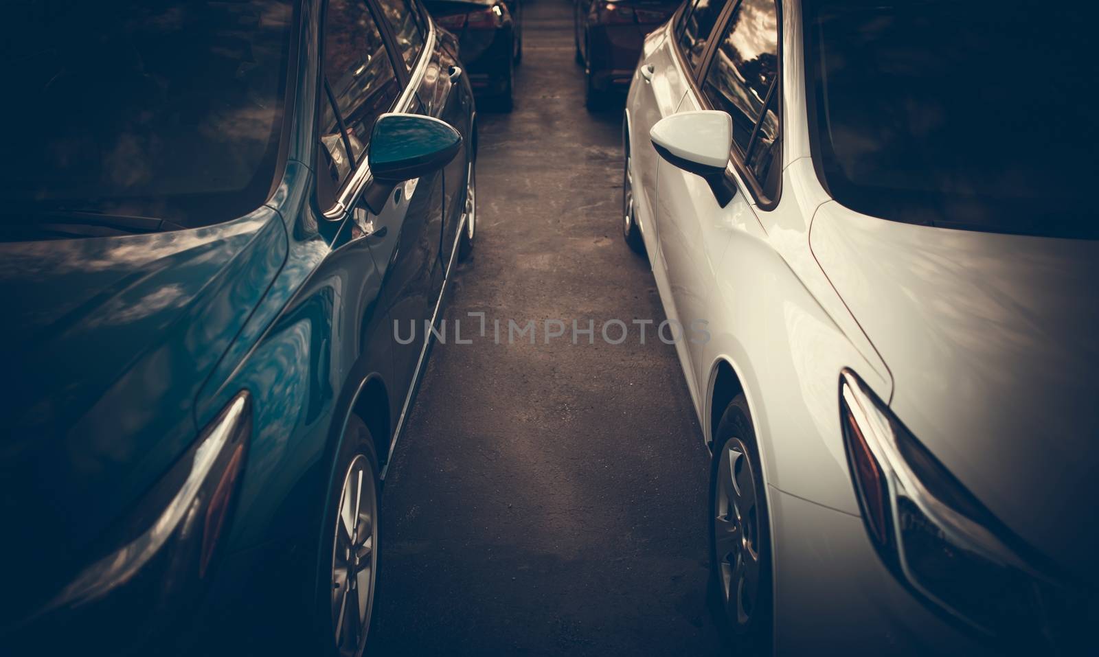 Tight Car Parking Spaces Theme. Modern Vehicles Side by Side Closeup Photo.