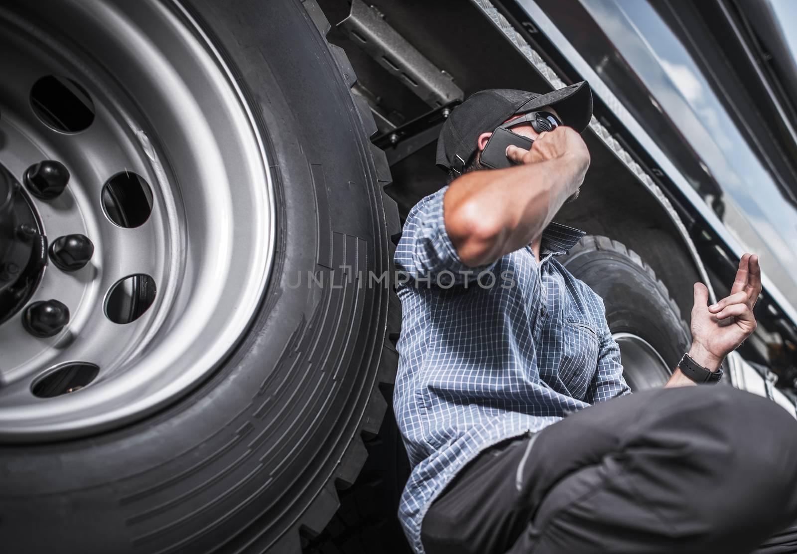 Truck Driving Business Concept. Caucasian Trucker on the Phone Next to His Vehicle.