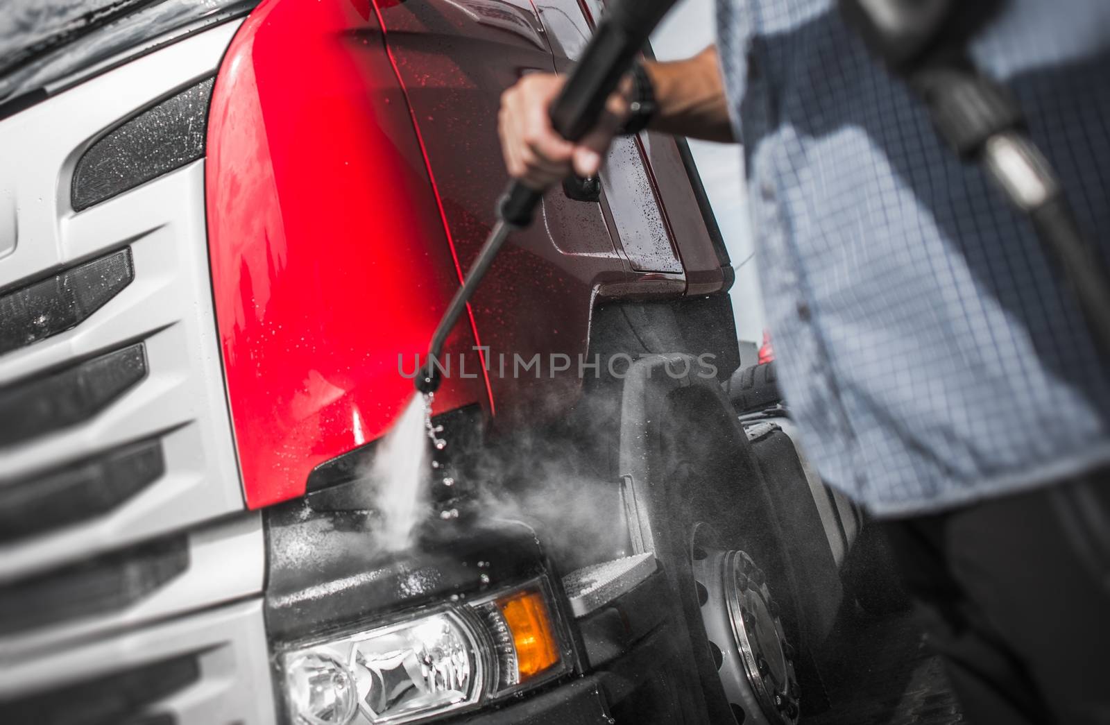 Trucker Washing His Semi Truck Using High Pressured Water Jet Cleaner.