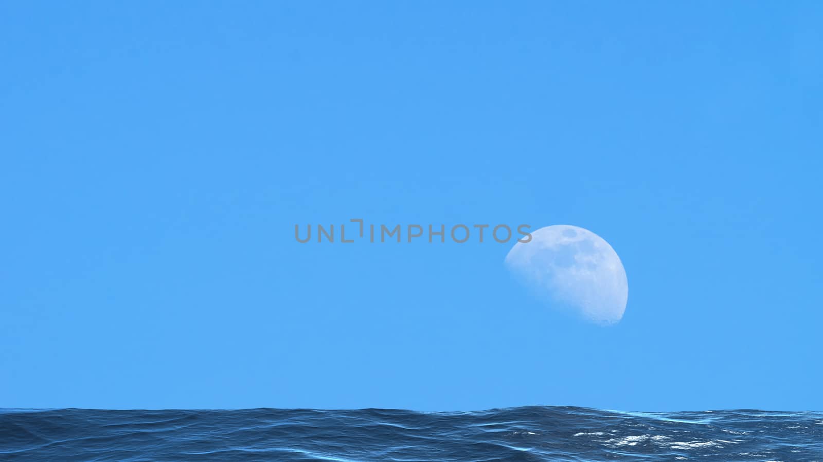Moon over the blue wide sea with reflections