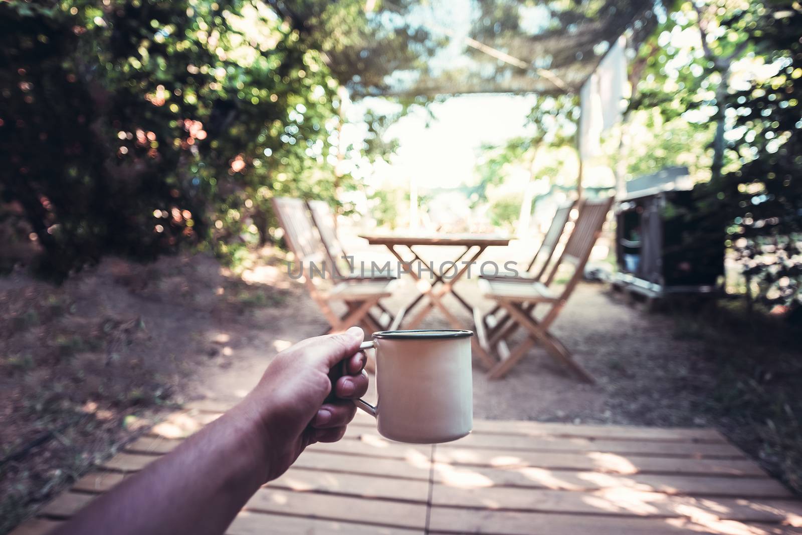 view of a hand of a hiker person resting with a cup in a camping, travel discovery concept, point of view shot