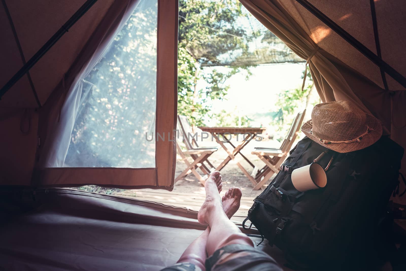 view of crossed feet of a hiker man resting barefoot in a camping tent, travel discovery concept, point of view shot
