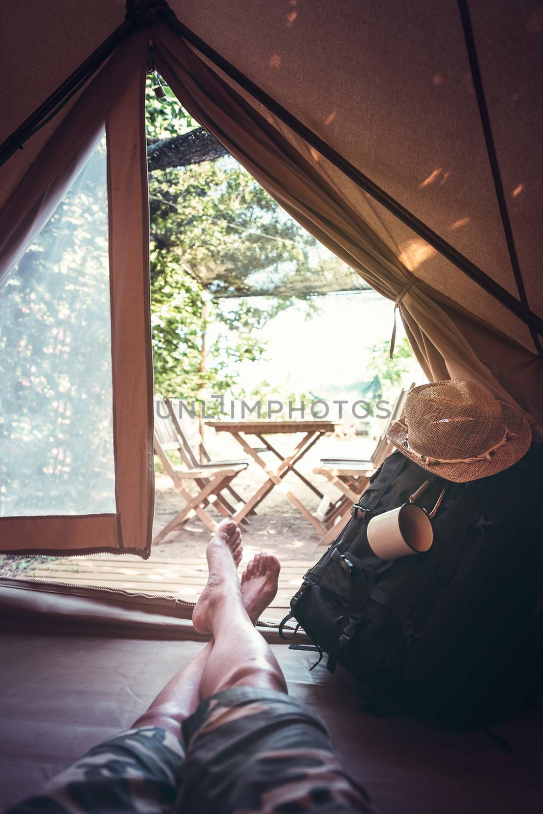 vertical view of crossed feet of a hiker man resting barefoot in a camping tent, travel discovery concept, point of view shot