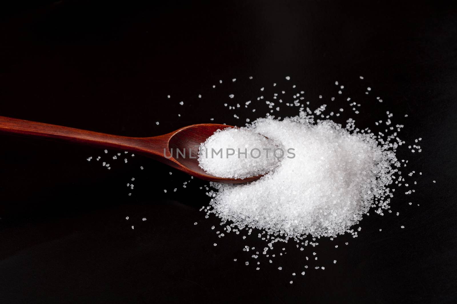 Brown Wood Spoon On Pile of White Salt Crystals Isolated on Black Background