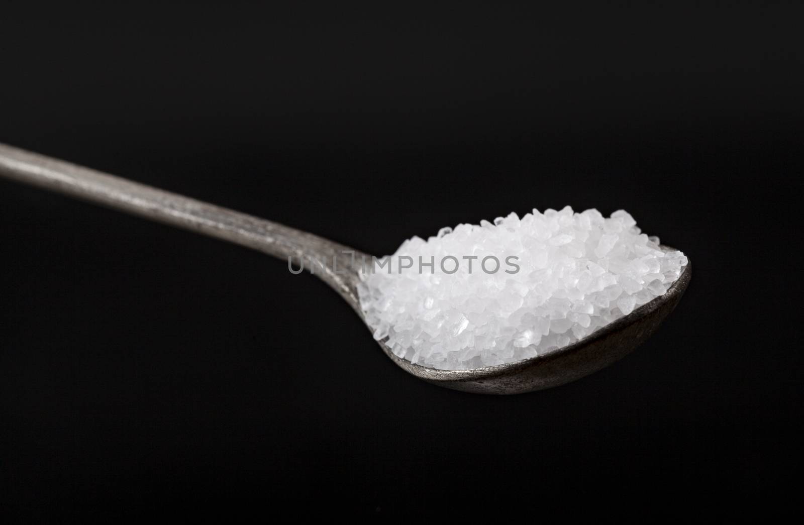 Silver Spoon Full With White Salt Crystals On Black Background