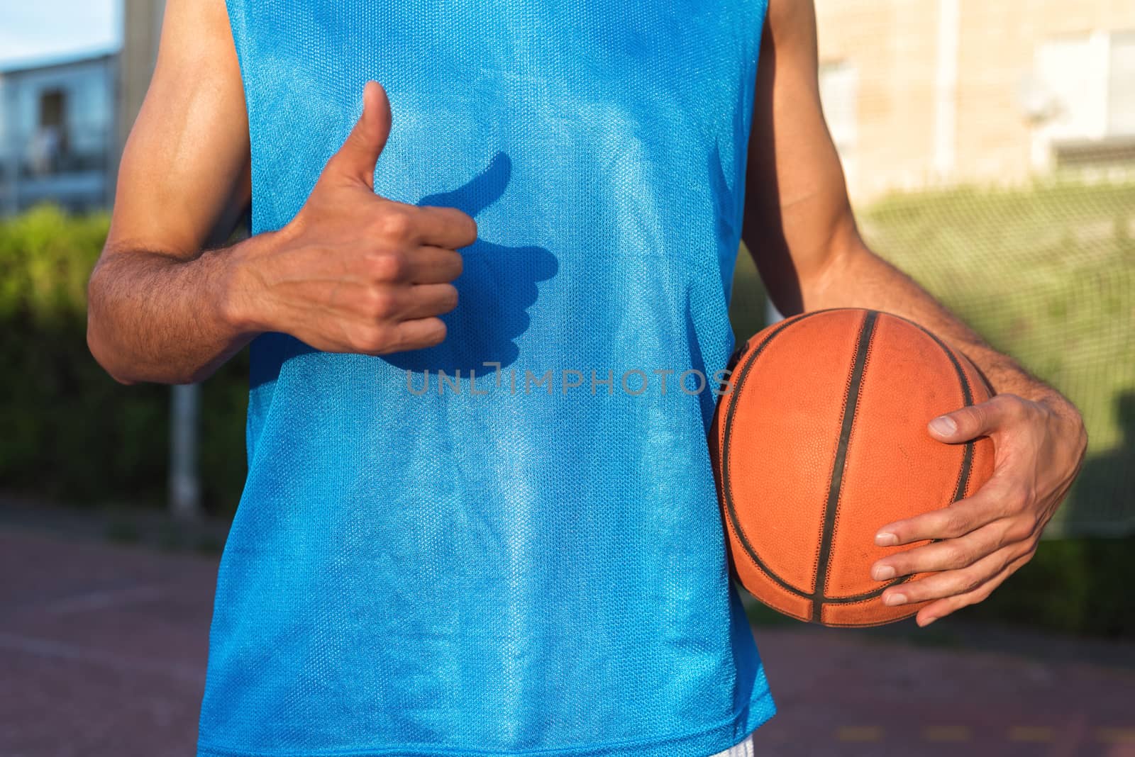 Athlete holding basketball ball with thumb up by HERRAEZ