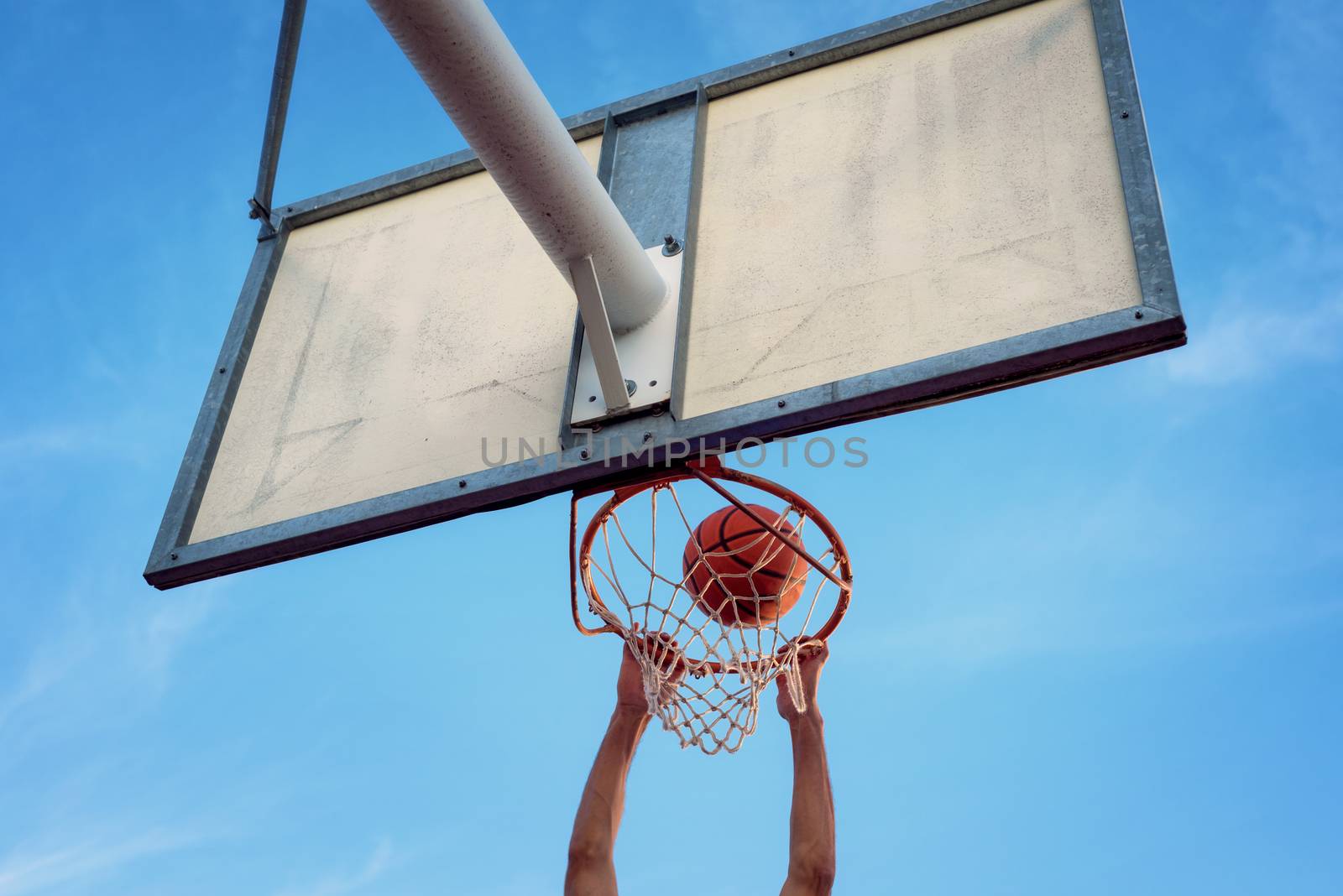 Street basketball athlete performing slam dunk on the court by HERRAEZ