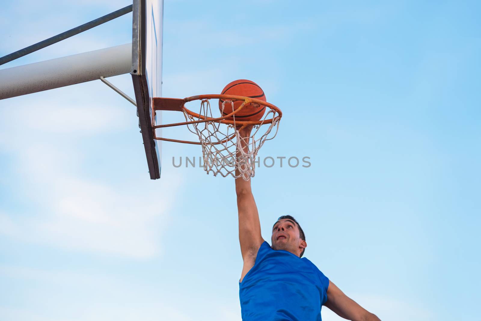 Street basketball athlete performing slam dunk on the court