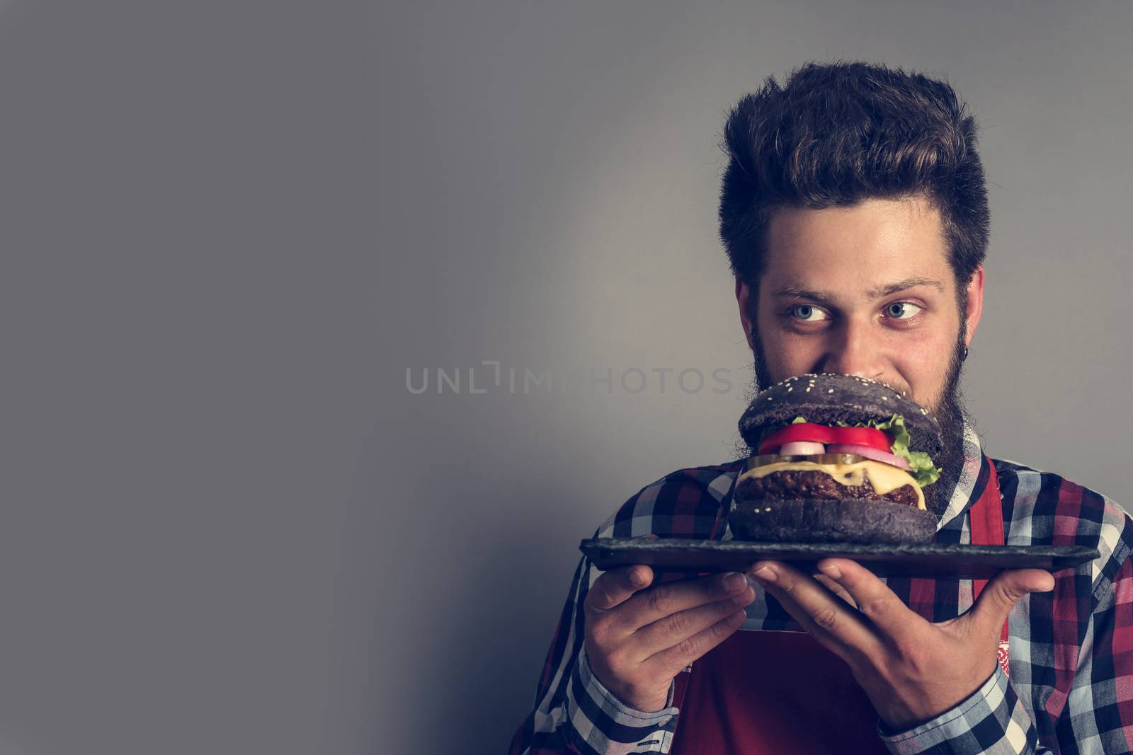 Man smelling fresh self made black burger close up