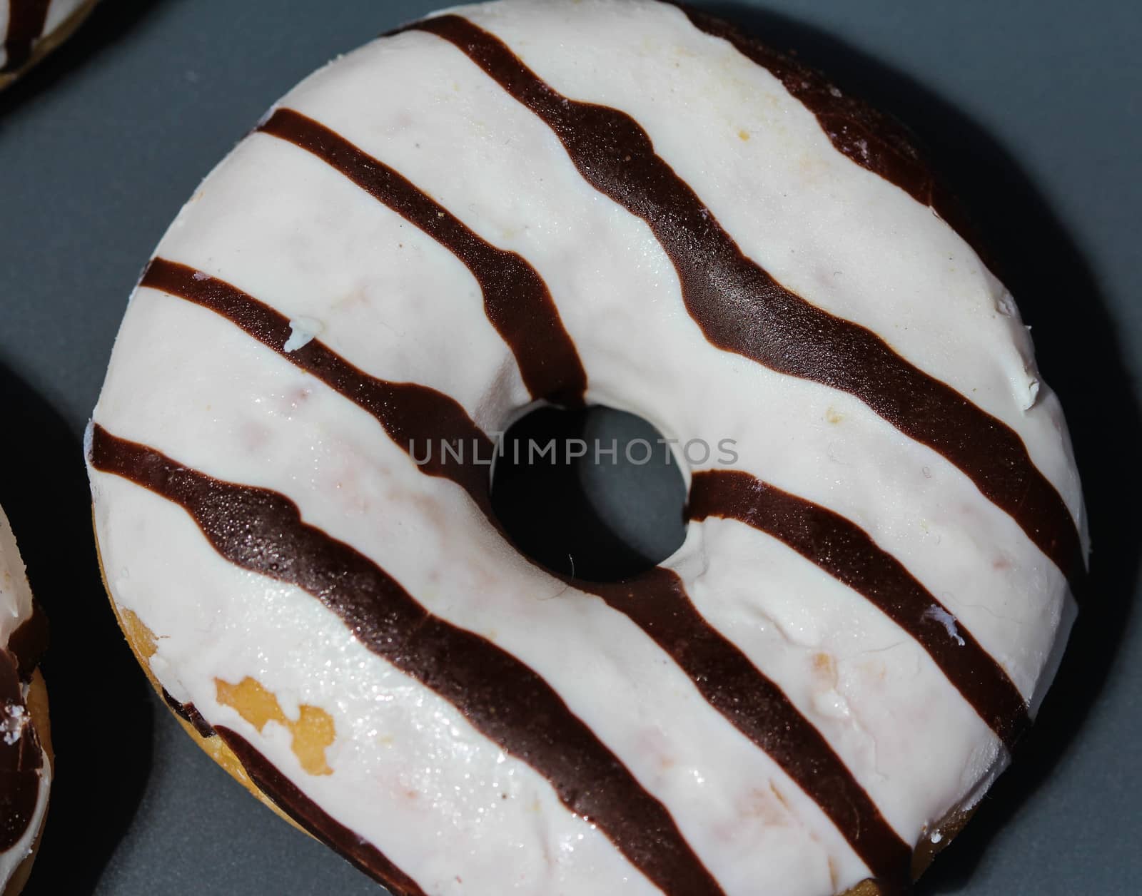 close up of vanilla donuts on table. The donuts have white glaze with brown chocolate