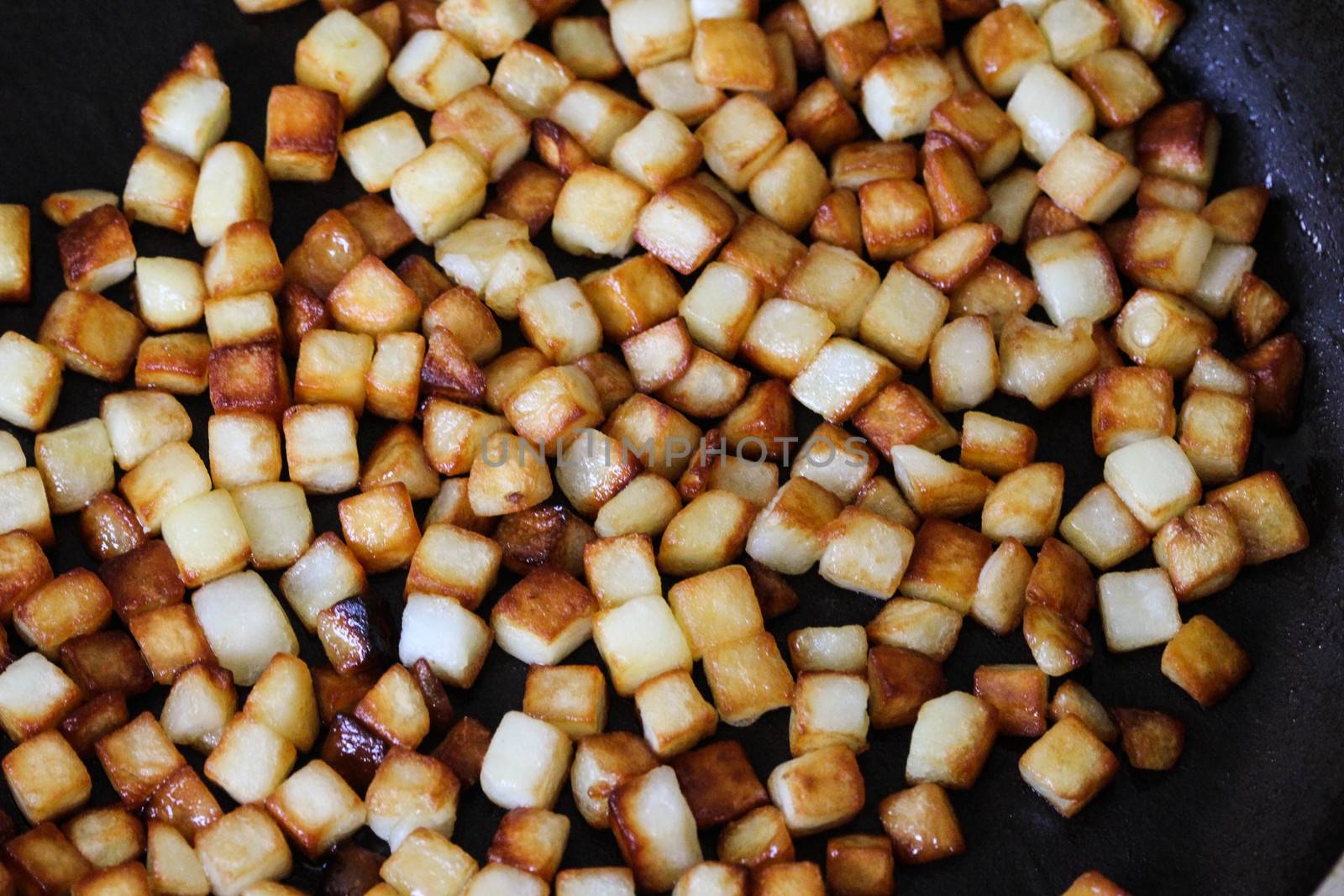 close up of baked potato cubes in pan in kitchen