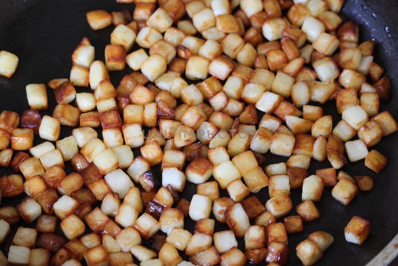 close up of baked potato cubes in pan in kitchen