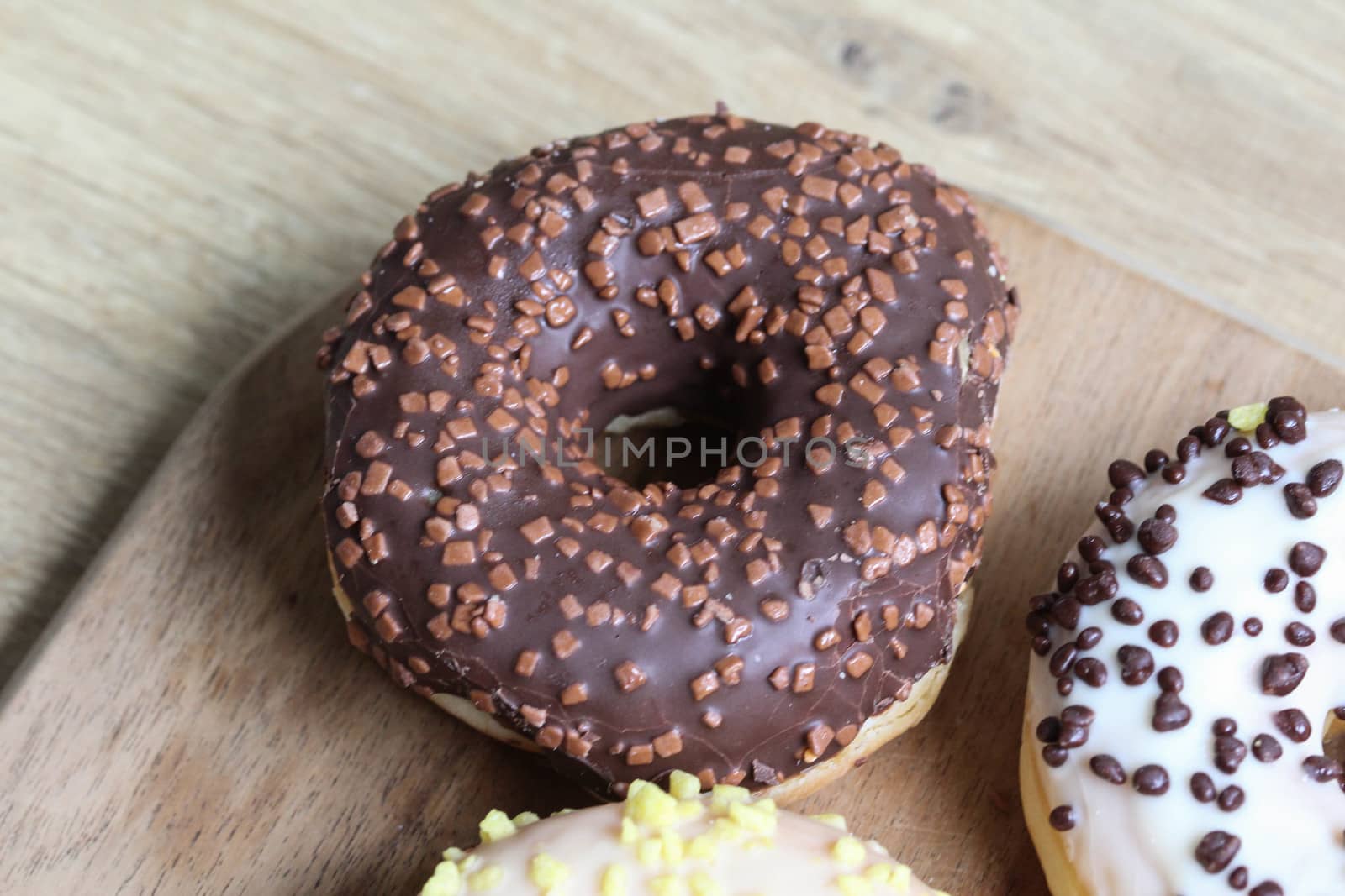 close up of a single strawberry donut with sprinkles on a wooden background
