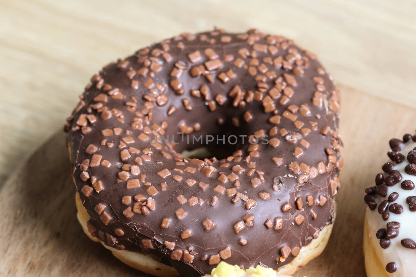 close up of a single strawberry donut with sprinkles on a wooden background
